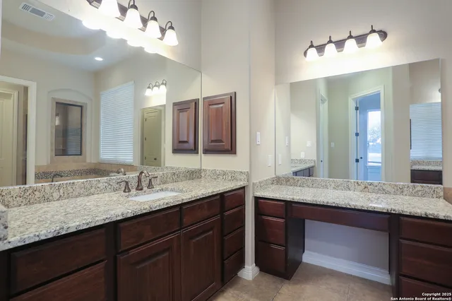 a bathroom with a granite countertop double vanity sink and a mirror
