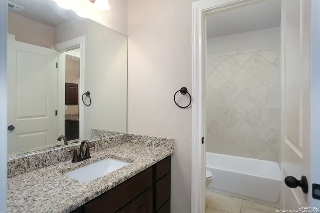 a bathroom with a granite countertop sink and a mirror