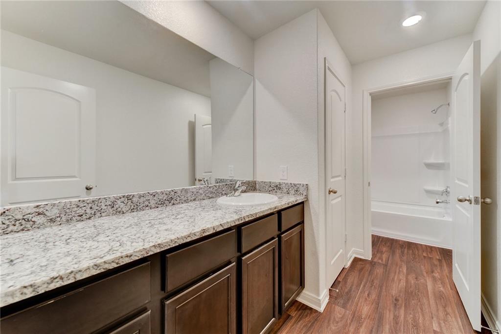 105 Brunswick Lane Jarrell, TX 76537 - Photo 16 of 18 a bathroom with a granite countertop sink a toilet and shower