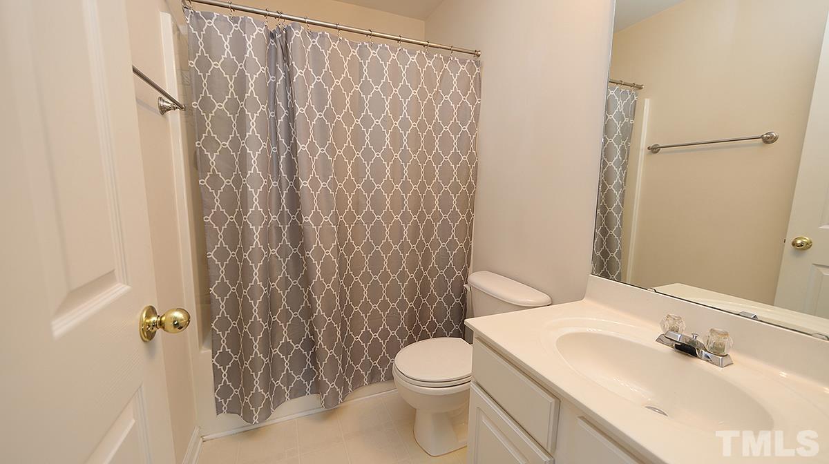 7225 Galon Glen Road Raleigh, NC 27613 - Photo 18 of 20 a bathroom with a sink a toilet and shower curtain