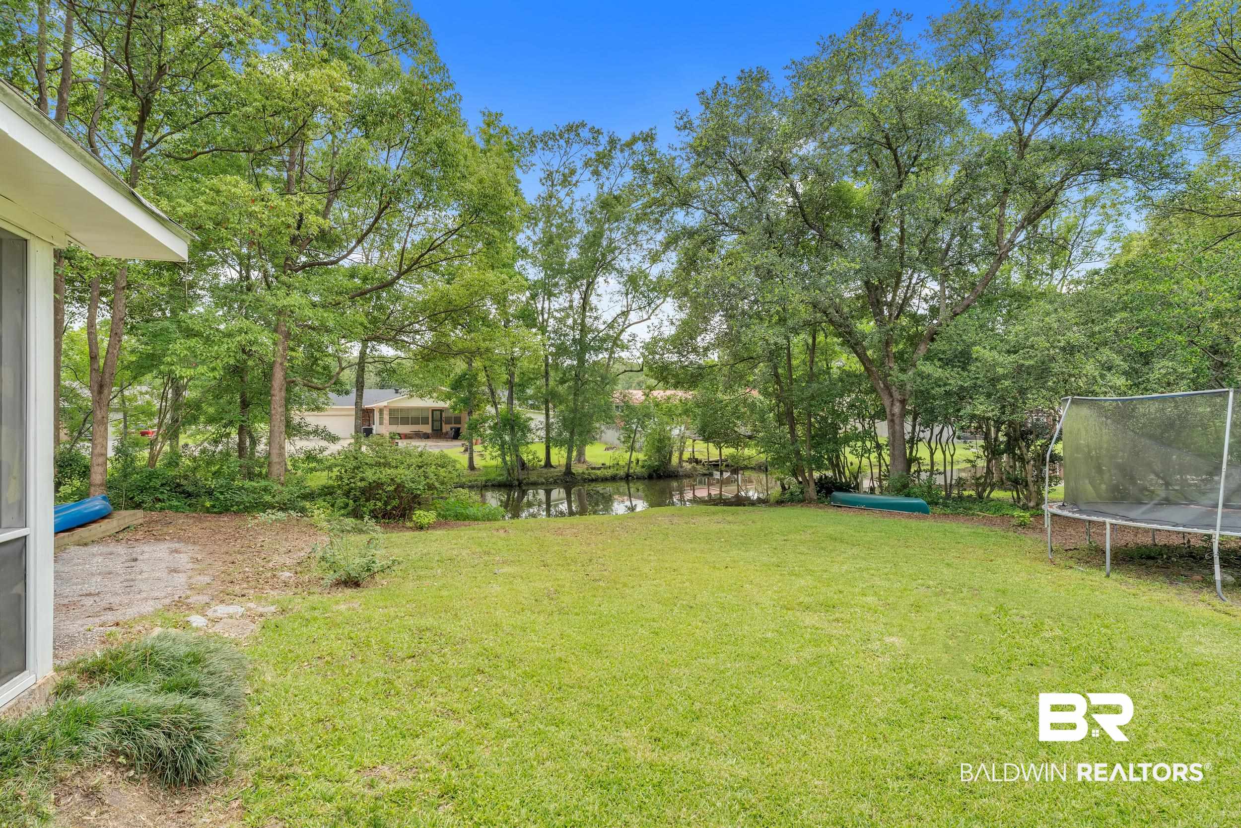 224 Cache Circle Mobile, AL 36611 - Photo 39 of 42 View of green lawn featuring a trampoline and a water view