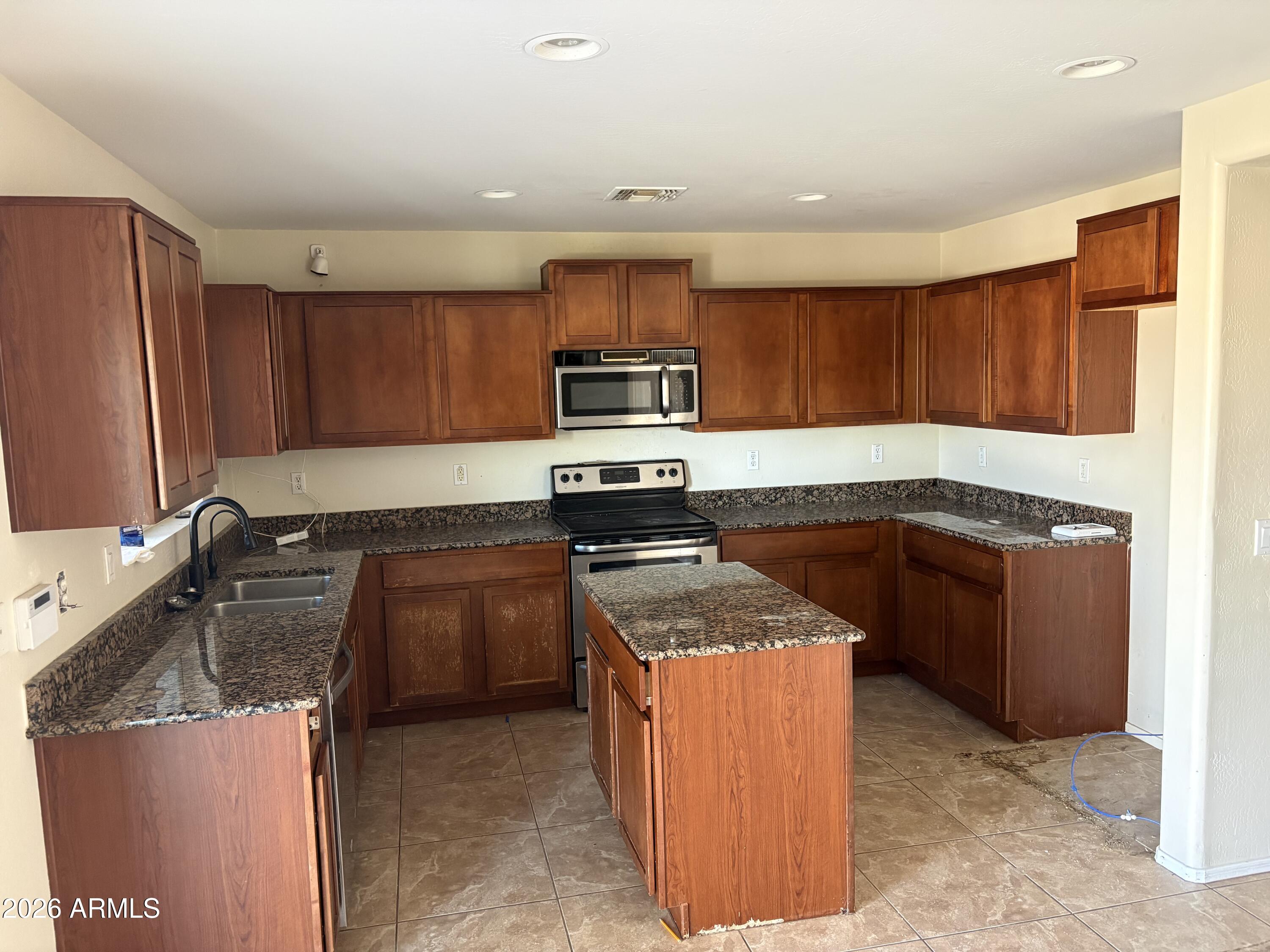 5222 East Silverbell Road San Tan Valley, AZ 85143 - Photo 4 of 16 a kitchen with granite countertop stainless steel appliances and wooden cabinets
