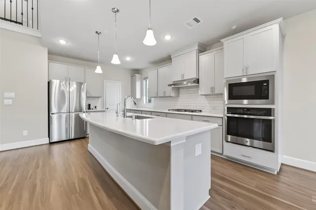 a large kitchen with stainless steel appliances kitchen island a large counter top and a refrigerator