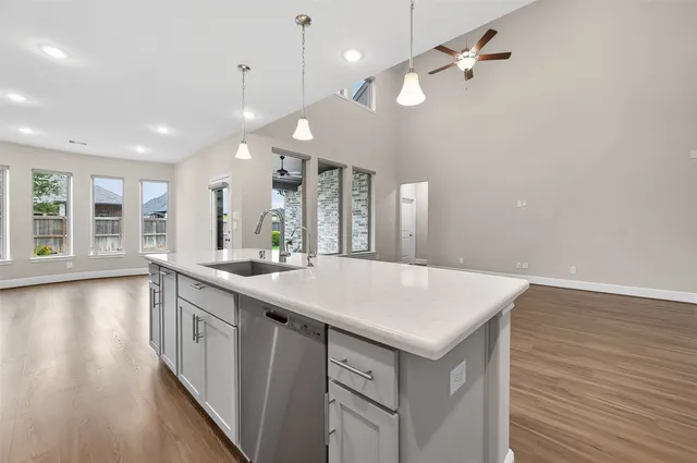 a large white kitchen with a large island oven a sink appliances and a large window