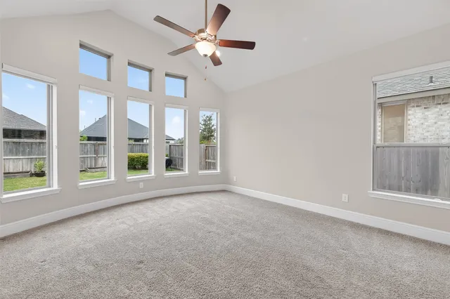 an empty room with windows and ceiling fan