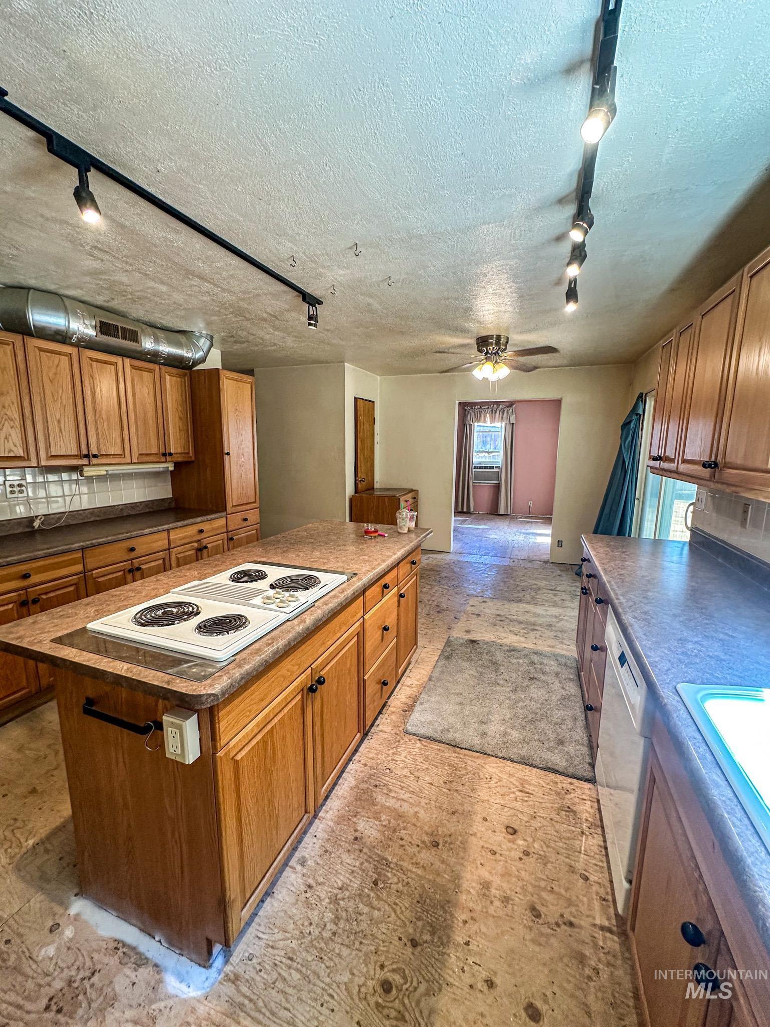404 Harmony Heights Road Orofino, ID 83544 - Photo 14 of 35 Kitchen featuring track lighting, brown cabinets, light flooring, a kitchen island, and a textured ceiling