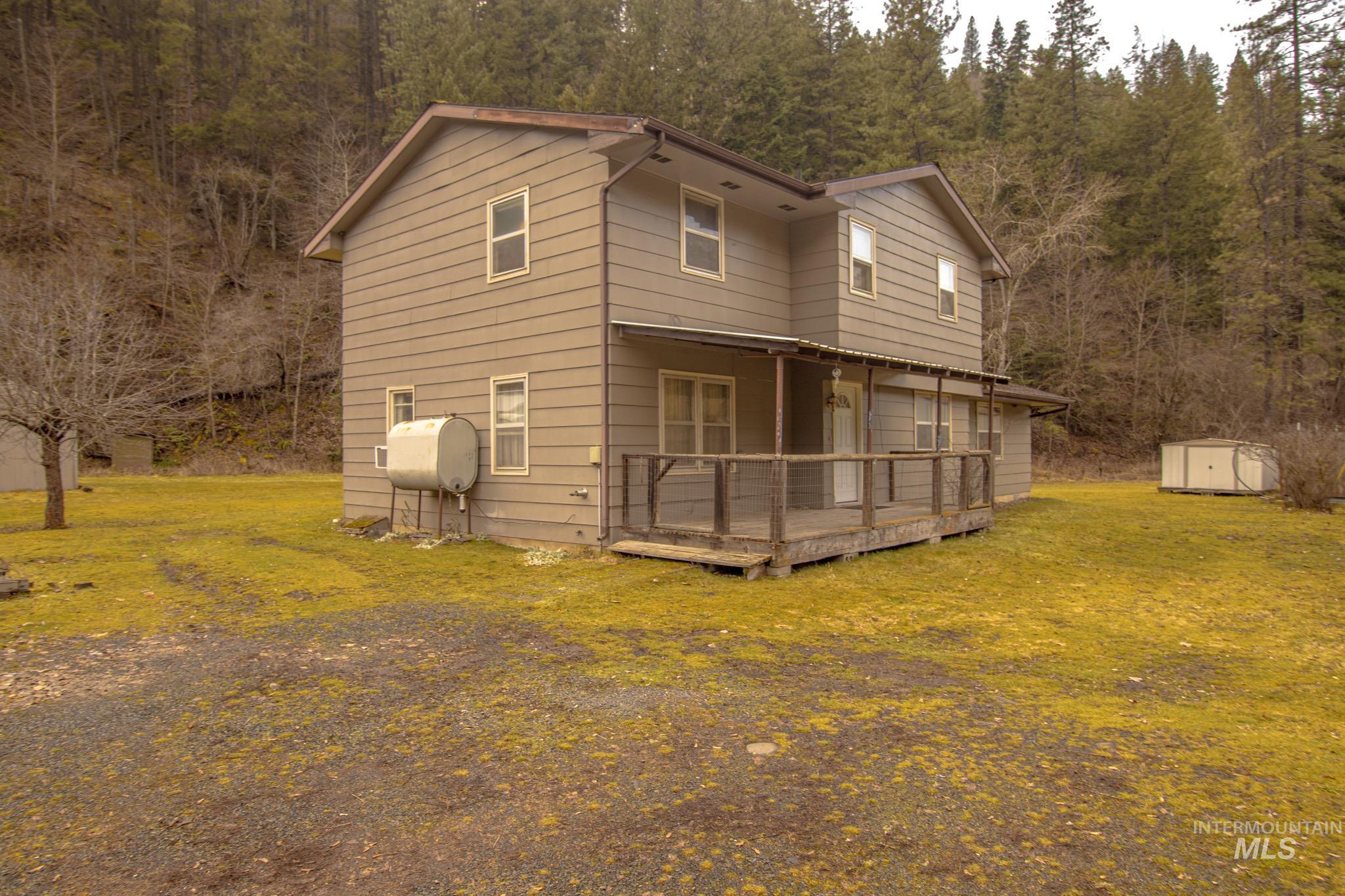 404 Harmony Heights Road Orofino, ID 83544 - Photo 32 of 35 side of house with a storage unit, a wooden deck, a lawn, heating fuel, and a forest view