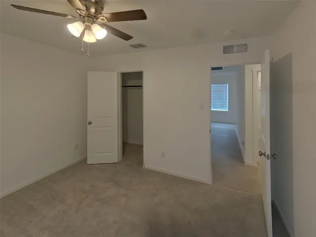 an empty room with a chandelier fan and closet area
