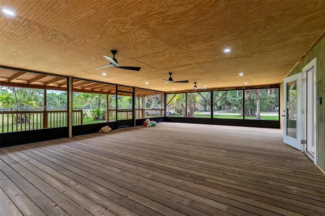 a view of an empty room with wooden floor and a balcony
