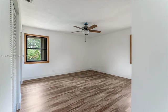 an empty room with a window and a ceiling fan