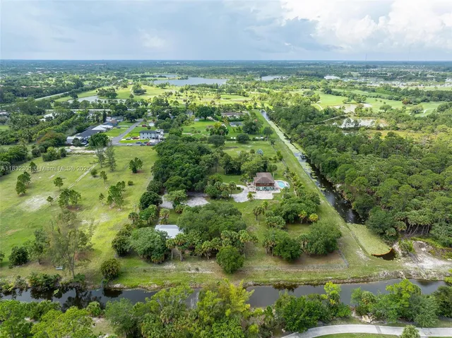 an aerial view of residential houses with outdoor space and trees