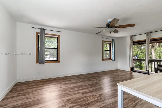 a view of an empty room with a window and wooden floor