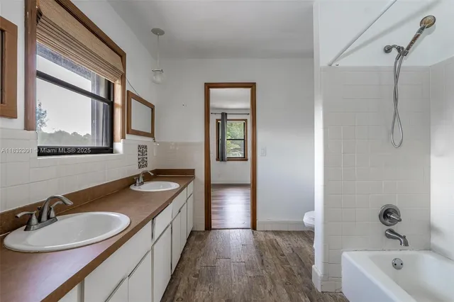 a bathroom with a granite countertop double vanity sink and mirror with bathtub