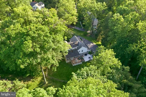an aerial view of residential house with outdoor space and trees all around