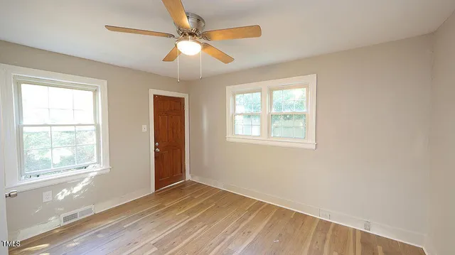 a view of an empty room with wooden floor and a window