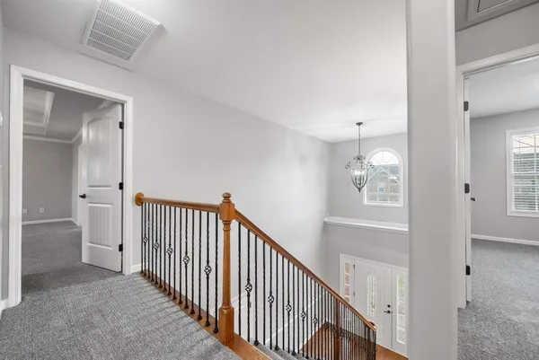 a view of an empty room with chandelier fan and fire place