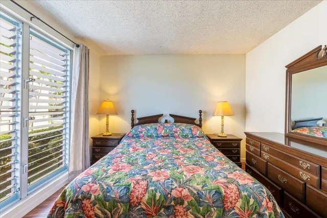 a bedroom with a bed and a flat tv screen on dresser