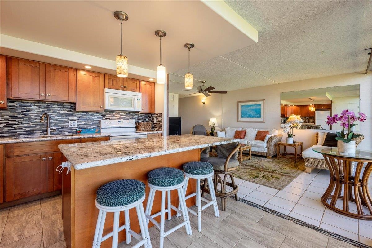 1002 South Kihei Road, Unit 212 Kihei, HI 96753 - Photo 5 of 50 a open kitchen with stainless steel appliances granite countertop a stove a sink a dining table chairs and chandelier