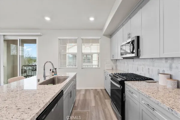 a kitchen with granite countertop a sink a stove and cabinets