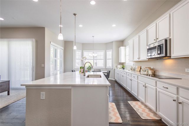 a kitchen with kitchen island granite countertop a sink a counter space appliances and cabinets