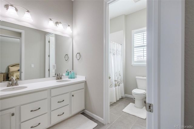 a spacious bathroom with a double vanity sink a mirror and a toilet