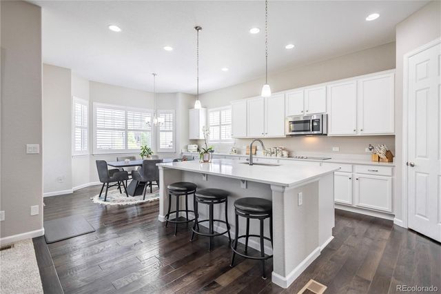 a kitchen with a table chairs sink microwave and cabinets