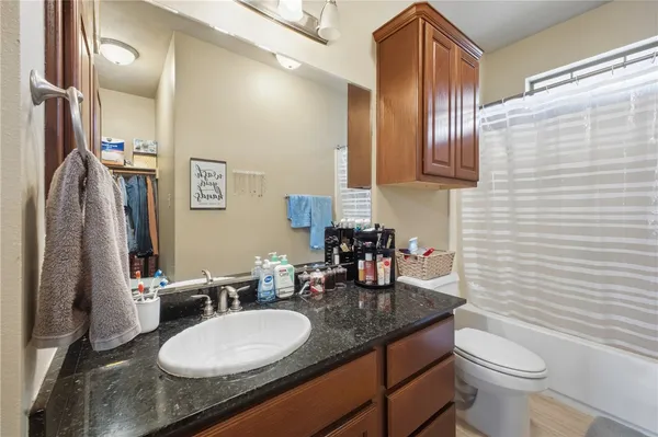 a bathroom with a granite countertop sink toilet and mirror