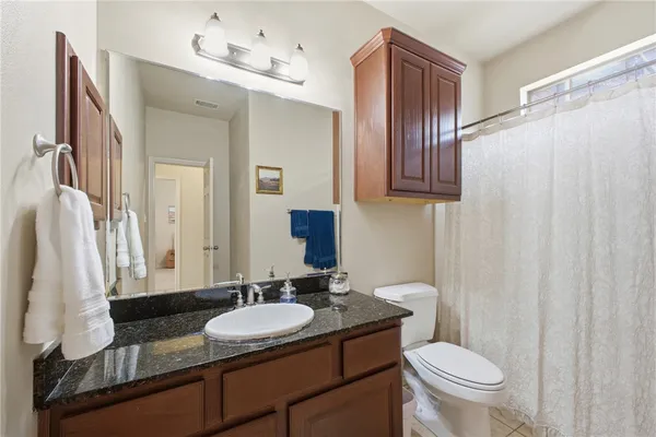 a bathroom with a granite countertop sink toilet and mirror
