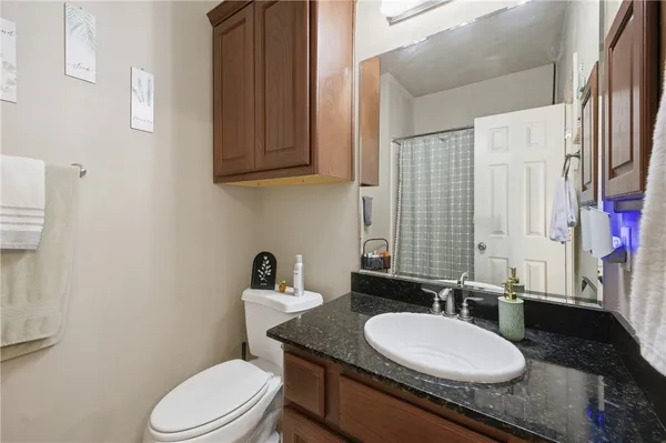 a bathroom with a granite countertop toilet sink and mirror