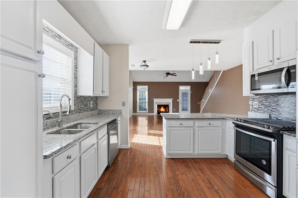1402 Edgeley Way Lawrenceville, GA 30044 - Photo 9 of 23 a kitchen with stainless steel appliances granite countertop hardwood floor sink stove and wooden cabinets
