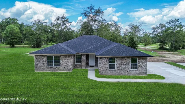 a view of a house with a yard potted plants and large tree