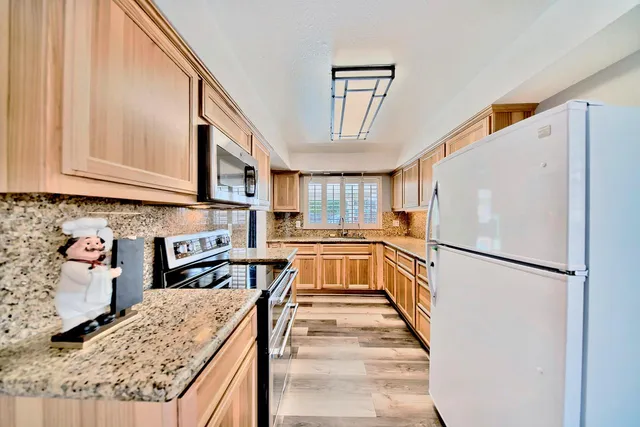 a kitchen with stainless steel appliances granite countertop a refrigerator a stove and a sink