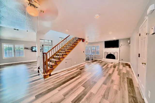 a view of an empty room with wooden floor and a fireplace