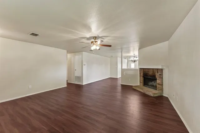 a view of an empty room with wooden floor and a fireplace