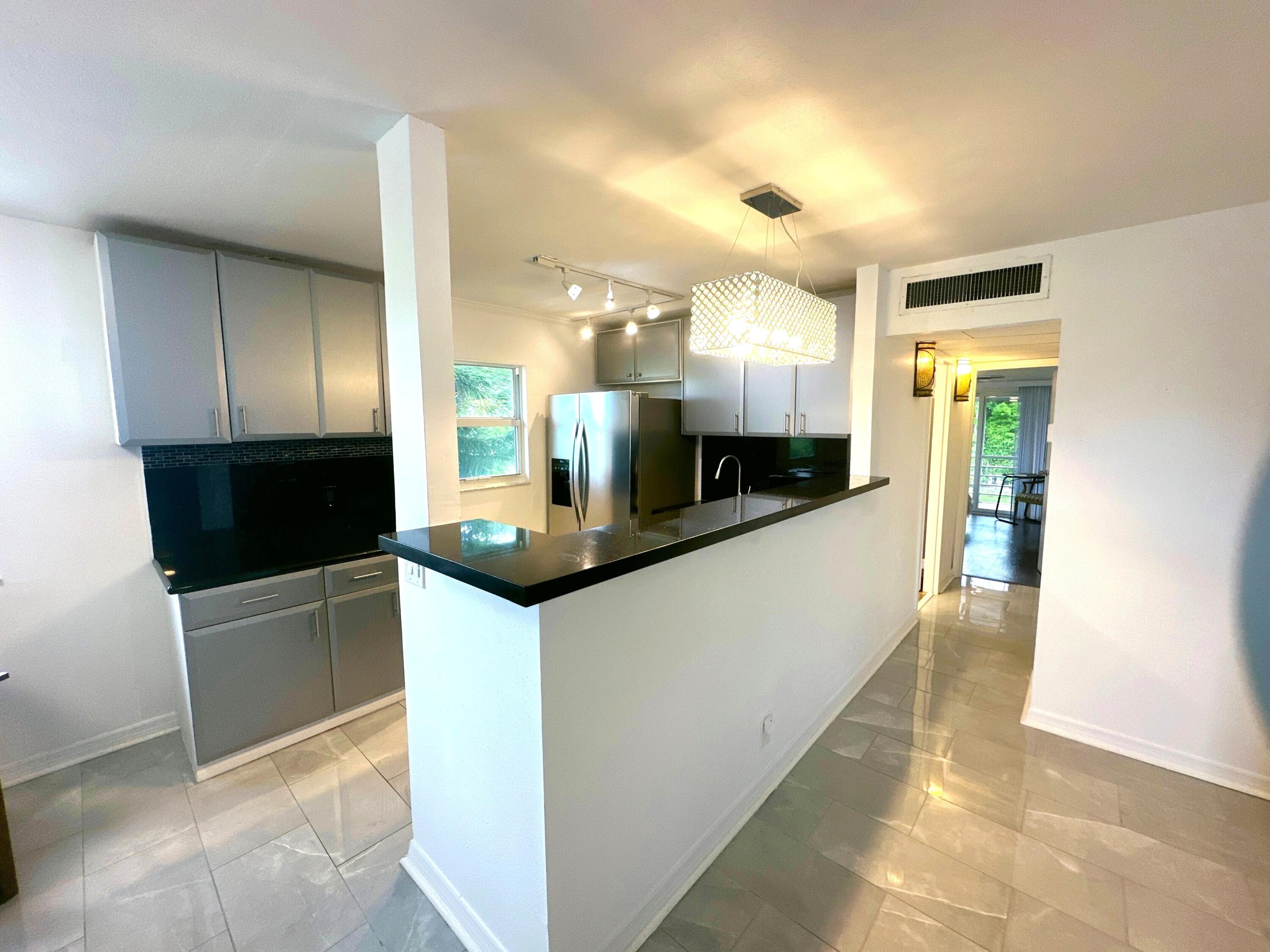 196 Tuscany C Delray Beach, FL 33446 - Photo 4 of 39 a large white kitchen with a large counter top and stainless steel appliances