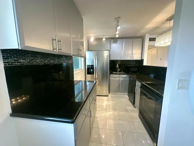 a kitchen with stainless steel appliances kitchen island granite countertop a stove a refrigerator and a microwave