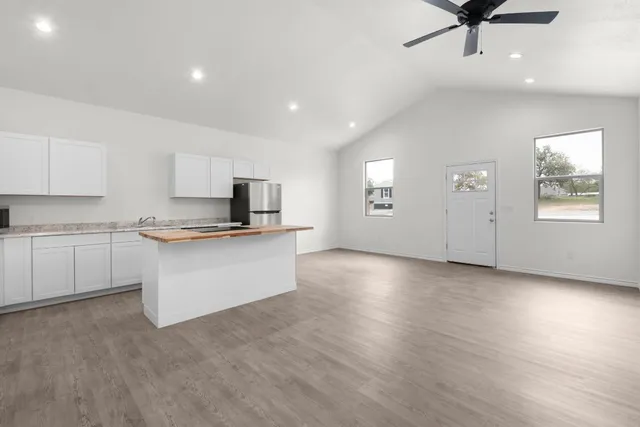 a kitchen with granite countertop a refrigerator sink and cabinets