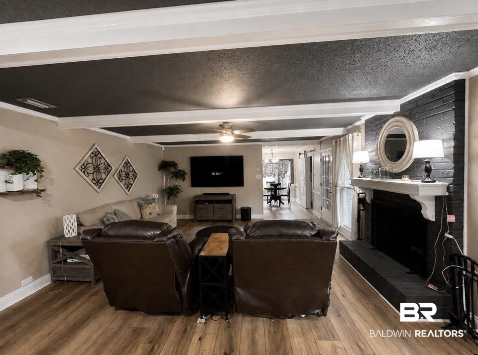 6429 Pinehurst Run Mobile, AL 36608 - Photo 7 of 15 Spacious living area featuring wood-finish flooring, a painted brick fireplace with a white mantel, and a dark textured ceiling with white beams