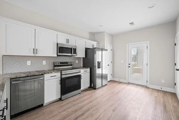 a kitchen with granite countertop white cabinets and stainless steel appliances