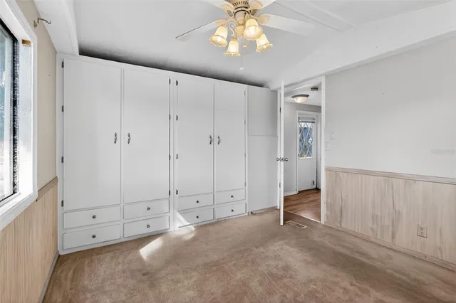 an empty room with chandelier fan and windows