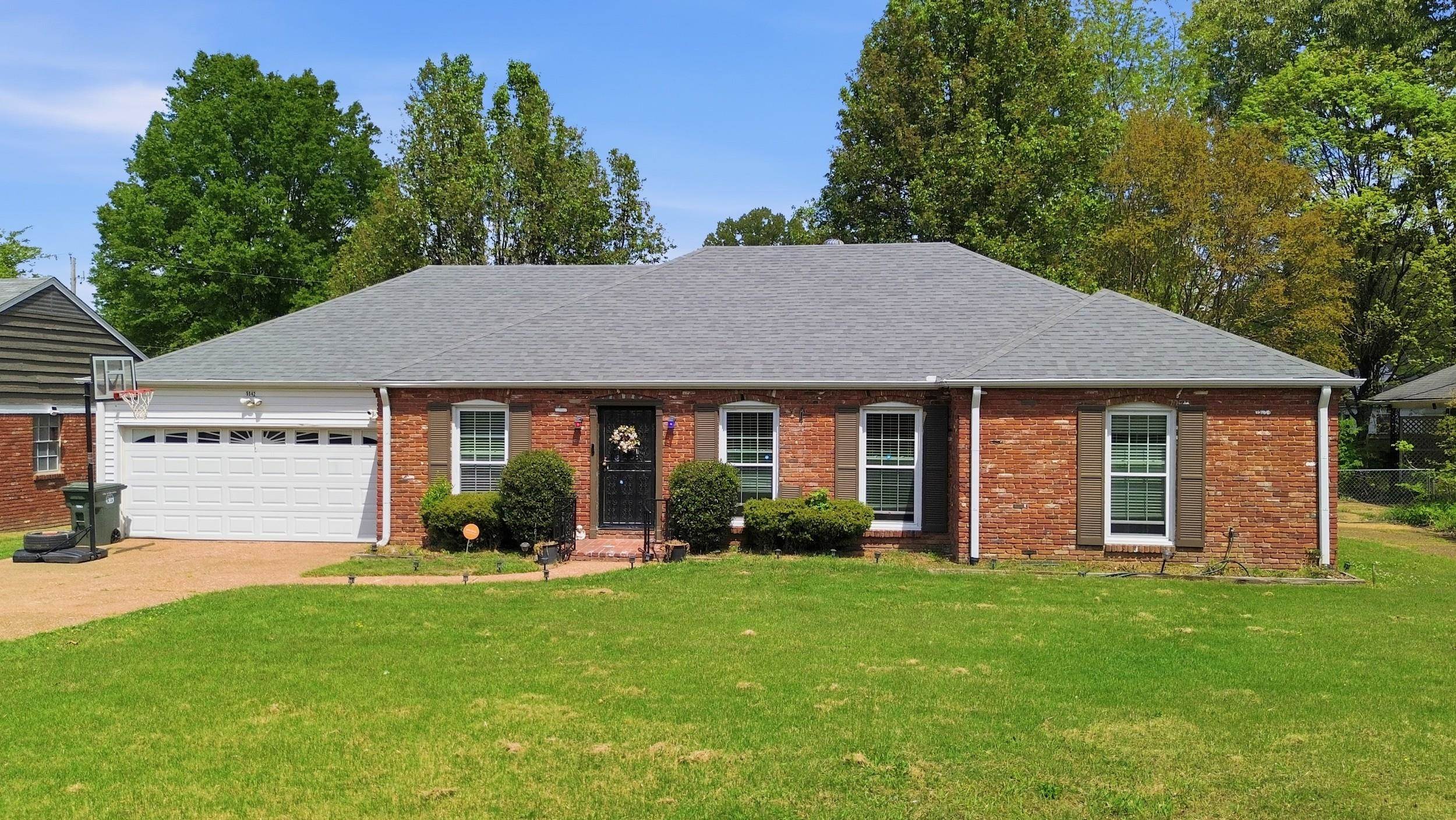 5542 Knight Arnold Road Memphis, TN 38115 - Photo 1 of 17 View of front of property with brick siding, a garage, a front yard, concrete driveway, and a shingled roof