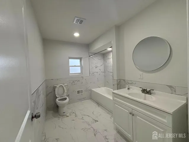 a spacious bathroom with a double vanity sink toilet mirror and bathtub