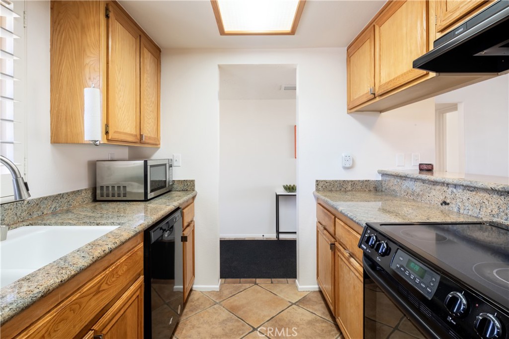 40657 Preston Trail Palm Desert, CA 92211 - Photo 20 of 46 a kitchen with granite countertop a sink a stove and a wooden cabinets