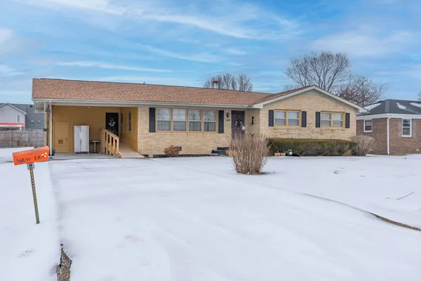 a front view of a house with a yard covered in snow