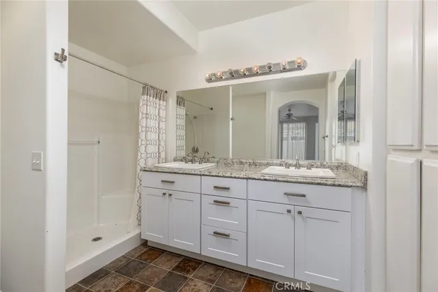 a bathroom with a granite countertop sink a mirror and a shower