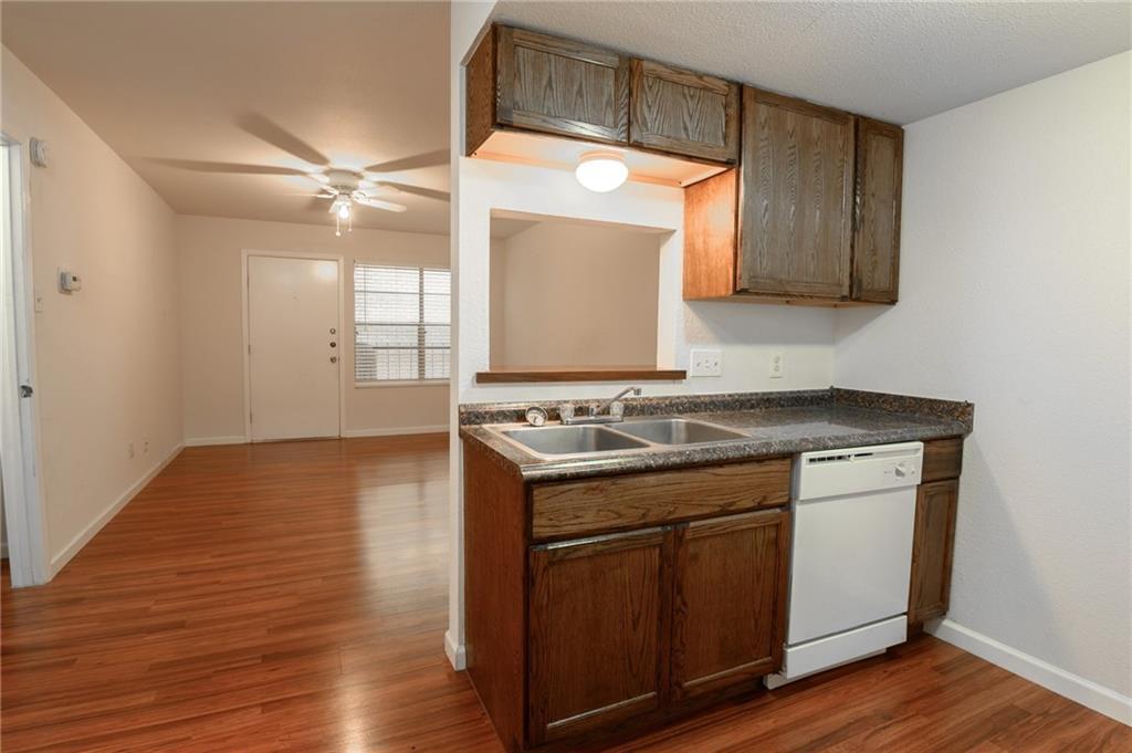 710 East Dean Keeton Street, Unit 207 Austin, TX 78705 - Photo 3 of 6 Functional kitchen with ample cabinet space opens to the living area, featuring rich hardwood flooring.