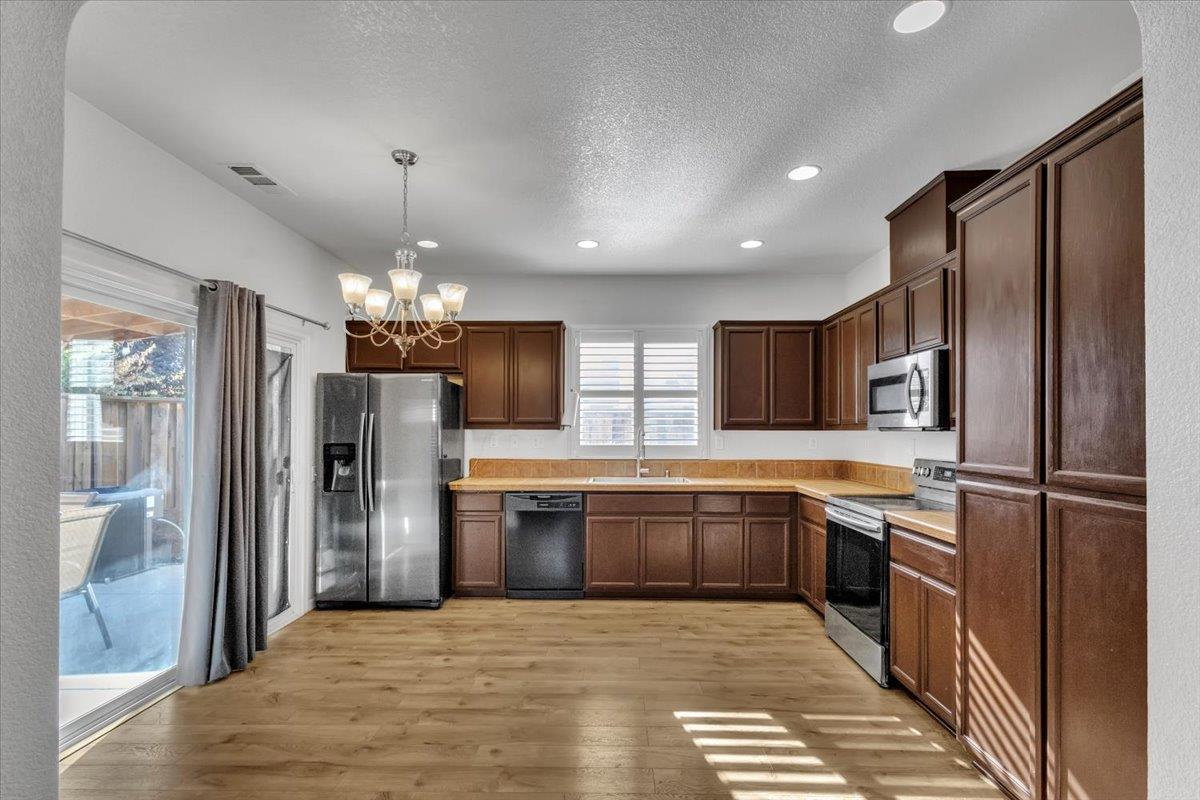 2608 Greenleaf Street Manteca, CA 95337 - Photo 14 of 65 a large kitchen with granite countertop a refrigerator and a sink