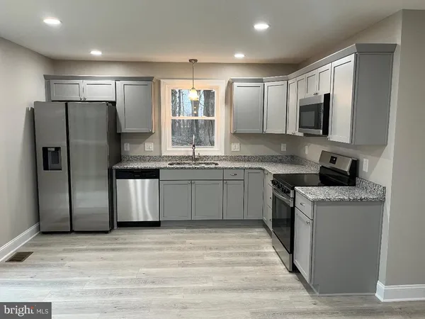 a kitchen with stainless steel appliances granite countertop a stove top oven a refrigerator and a sink