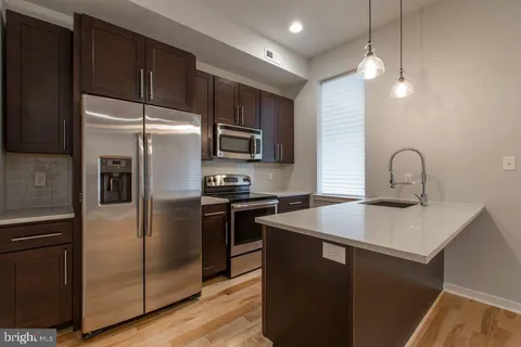 a kitchen with kitchen island a counter space a sink appliances and cabinets