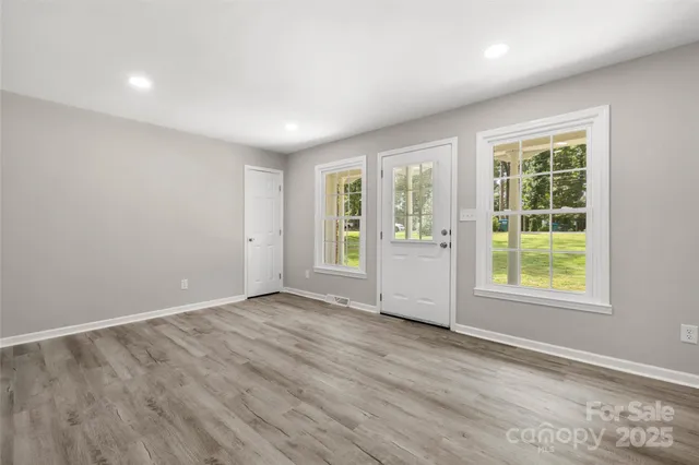 an empty room with wooden floor and windows